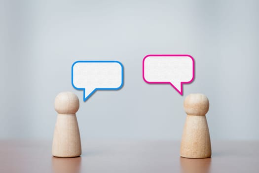 Wooden figurines facing each other with speech bubbles. Concept of communication, dialogue, teamwork, discussion, collaboration, and human interaction.