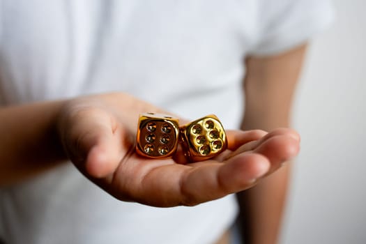 Hand holding gold dice close up.
