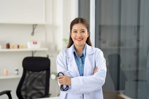 A confident healthcare professional stands with arms crossed, smiling in a clinic, representing professionalism and trust in patient care.