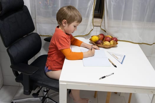Young boy writing on notebook sitting on an ergonomic office chair in his home