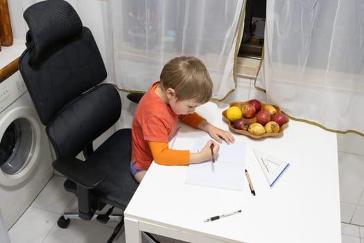 Young boy practicing drawing and writing on notebook, sitting on an ergonomic chair next to a bowl of fresh fruit