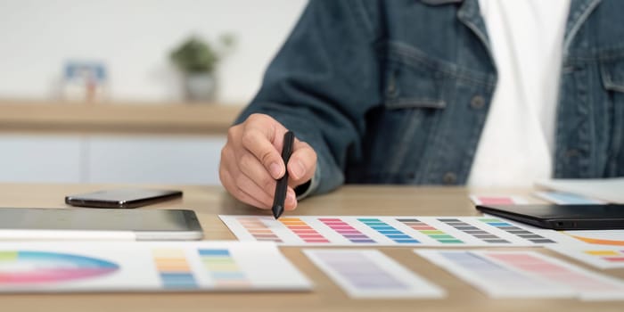 A designer selecting colors from a palette while using a digital pen on a tablet, showcasing creativity in a modern workspace.