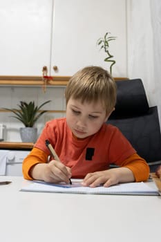 Young student doing homework and writing on notebook at home