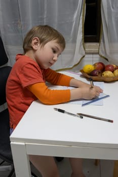 Young boy learning geometry and practicing drawing with pen, ruler and set square on squared paper