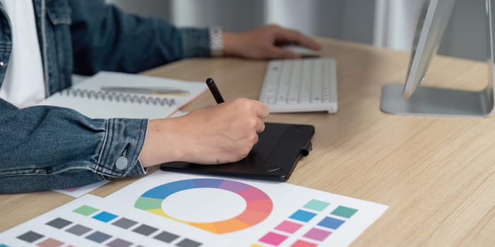 A designer actively sketches on a graphic tablet, exploring color palettes and enhancing creativity in a modern workspace.
