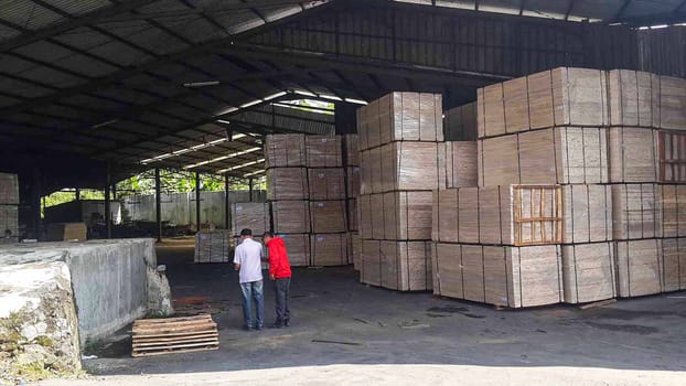 plywood processing plant showcasing Industrial Warehouse Interior with Stacks of Materials and Machinery, warehouse featuring industrial equipment, materials, and wooden pallets, highlighting productivity and organization.