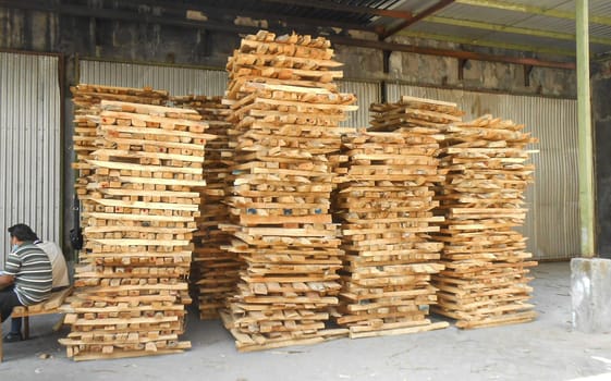 plywood processing plant showcasing Industrial Warehouse Interior with Stacks of Materials and Machinery, warehouse featuring industrial equipment, materials, and wooden pallets, highlighting productivity and organization.