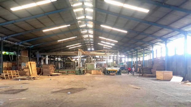 plywood processing plant showcasing Industrial Warehouse Interior with Stacks of Materials and Machinery, warehouse featuring industrial equipment, materials, and wooden pallets, highlighting productivity and organization.