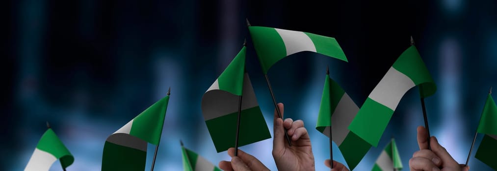 Nigeria flags in their hands on a blurred urban background. The photo illustration was created without the use of artificial intelligence, only using Photoshop.
