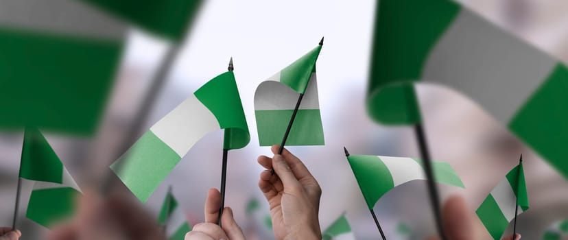 Nigeria flags in their hands on a blurred urban background. The photo illustration was created without the use of artificial intelligence, only using Photoshop.