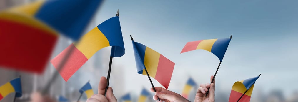 Chad flags in their hands on a blurred urban background. The photo illustration was created without the use of artificial intelligence, only using Photoshop.