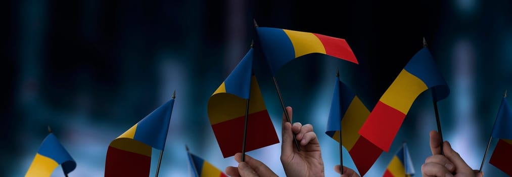 Chad flags in their hands on a blurred urban background. The photo illustration was created without the use of artificial intelligence, only using Photoshop.