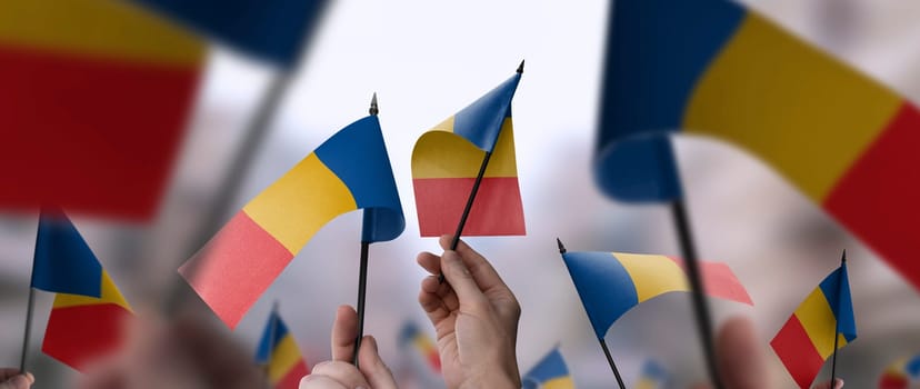 Chad flags in their hands on a blurred urban background. The photo illustration was created without the use of artificial intelligence, only using Photoshop.