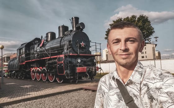 Handsome man male tourist with classic vintage old retro train trains steam locomotive locomotives in the Railway engineering museum in Leninskiy Rayon Brest Belarus.