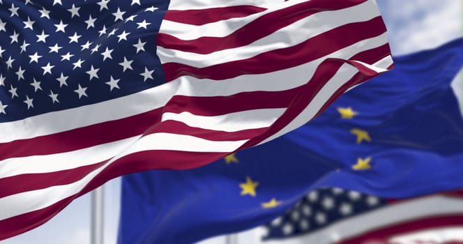 The flags of the United States of America and the European Union waving in the wind on a clear day. 3D illustration render. Rippled fabric. Selective focus. International politics, alliance