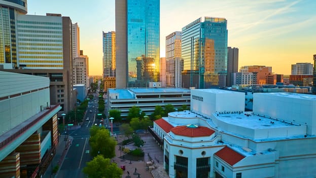 Golden hour aerial view of downtown Phoenix Arizona with modern glass skyscrapers shining in sunlight and the iconic Herberger Theater Center adding cultural flair to the vibrant cityscape