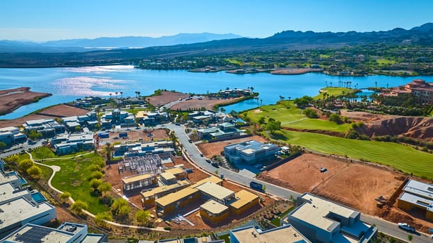 Aerial view of luxury lakeside homes under construction beside a lush golf course at Lake Las Vegas Nevada with blue water and scenic mountains in the background ideal for real estate and lifestyle themes