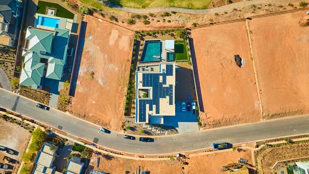 Aerial view of a modern solar-powered home with pool in upscale Lake Las Vegas neighborhood Nevada showing new construction sites and green living in a desert community on a bright sunny day