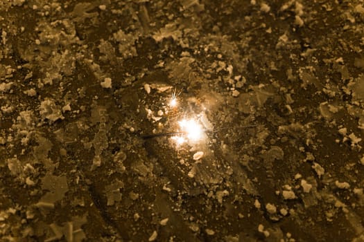 Sparkler burns on winter pavement. Concept of celebration, magic, fleeting moment in urban setting.