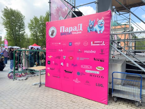 Moscow, Russia, April 27, 2025: Bright pink sponsor board featuring logos of pet related brands stands beside the main stage at the French Bulldog Parade in Vorontsovsky Park