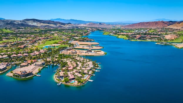 Aerial view of a luxurious lakeside community in Lake Las Vegas Nevada featuring upscale waterfront homes lush landscaping and clear blue water set against a dramatic desert mountain backdrop