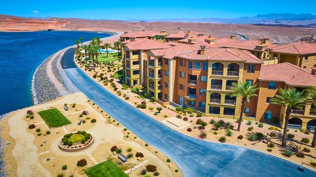 Aerial view of luxury Mediterranean-style waterfront condos with terracotta roofs and palm-lined grounds on Lake Las Vegas Nevada surrounded by desert landscape and rugged mountains under clear blue sky