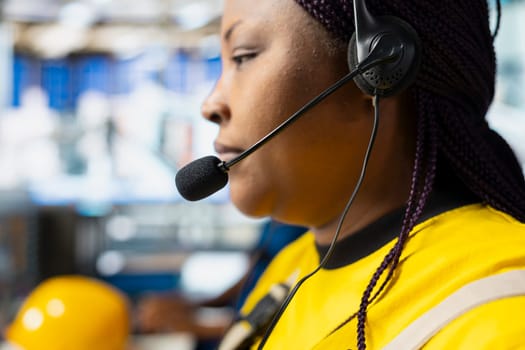 Solar power female engineer giving remote support on headset call in factory, working in customer service call center. Operator sales representative gives assistance, industrial facility.