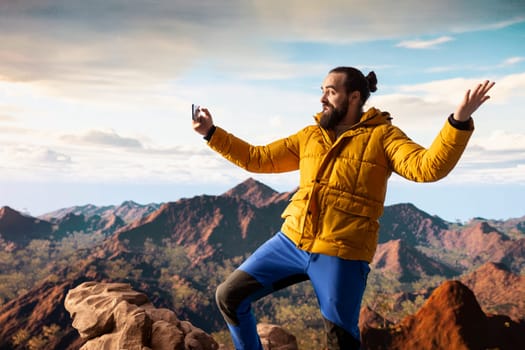 Travel influencer with strong signal live streaming from the mountain top, recording a vlog for his audience and social media channel. Young hiker trekking and creating content.