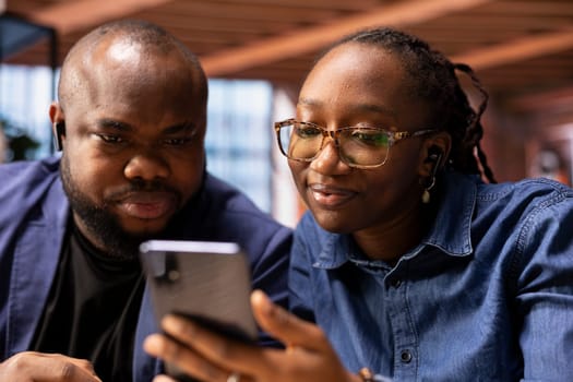 Confident black couple greeting colleagues on a video conference discussion, enjoying the benefits of a remote job through online communication from their home. Virtual briefing meeting.