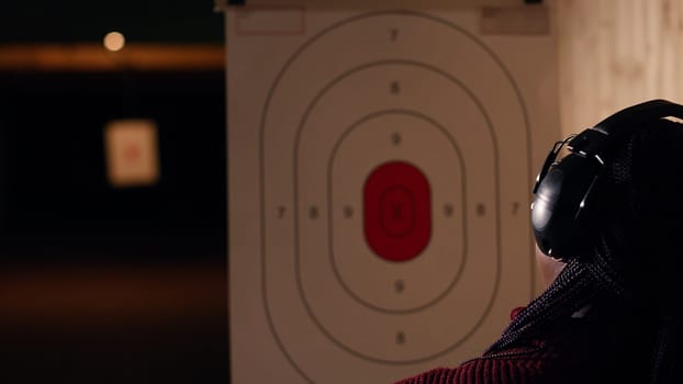 Friends in firing range doing recreational shooting, pressing mechanism to recall paper targets. People training with handguns, sharpening skills, checking points scored on bullseyes, camera B
