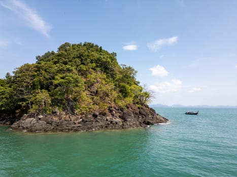 Drone shot of a sailboat cruising along Thailand exotic coastline, breathtaking scene of a motorboat navigating the turquoise waters. Passing by scenic coastal cliffs and a tropical shoreline.