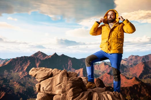 Nature lover stands at the edge of a breathtaking mountain range, looking at the scenic background of towering peaks and vast sky. Young man enjoying adventure and outdoor exploration.