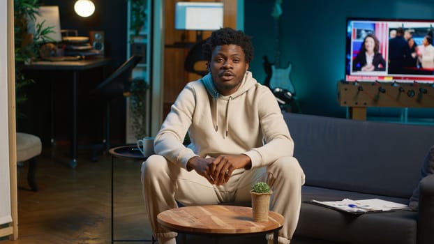 Black male student trying to learn a new language from his living room, attending an online course lesson to develop his skills. Ambitious person solving exercises and tasks remotely. Camera A.