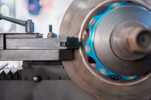 Car mechanic or serviceman disassembly and checking a disc brake and asbestos brake pads for fix and repair problem at car garage or repair shop
