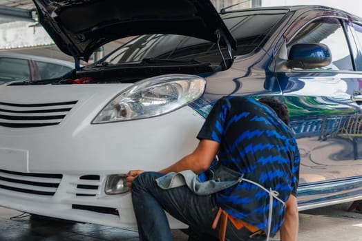 Denter or car mechanic serviceman check and fix body work and fiber bumper body part for fix and repair problem at car garage or repair shop