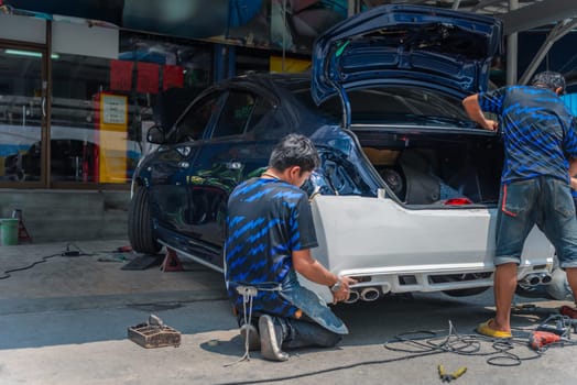 Denter or car mechanic serviceman check and fix body work and fiber bumper body part for fix and repair problem at car garage or repair shop