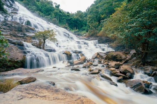 Beautiful waterfall with a lush green forest in the background. The water is flowing down the rocks and creating a beautiful scene. Sustainable waterfall in lush forest promoting water sustainability.
