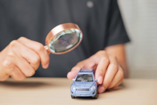 Magnifying glass focused on a car model, representing the search for automobile repair or insurance options. Concept of vehicle assessment and ensuring maintenance with careful inspection.