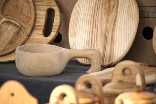 Rustic wooden kitchenware artfully arranged, including a kuksa cup, plates, and boards, showcases natural wood grain and craftsmanship.