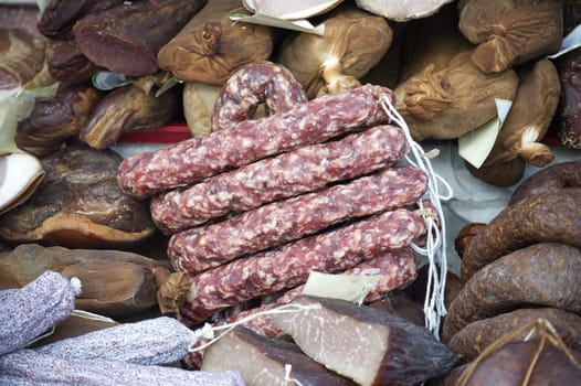 A close-up showcases an assortment of cured meats including sausages and cured meats, presenting a rustic culinary composition.