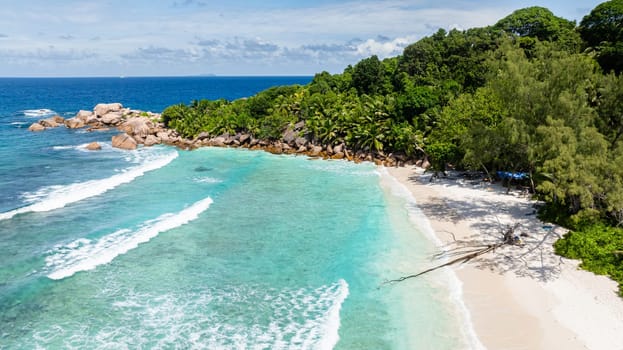 Clear turquoise waters gently meeting the sandy shore, creating a serene scene. La Digue, Seychelles.