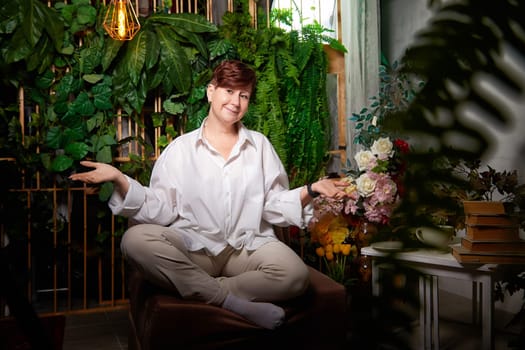 In a cozy room adorned with plants, a middle-aged woman expresses joy while engaging in her blogging activities.