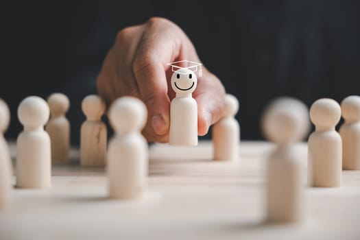 Hand picking a standout wooden figure for business hiring and recruitment. The chosen leader ensures success through teamwork and effective HR management.
