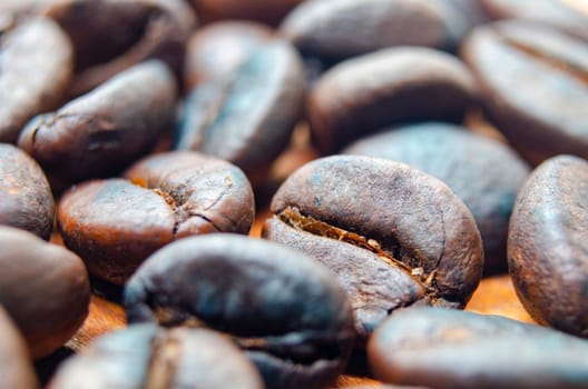 Side view of close up of roasted coffee beans that highlights the texture and surface details of the coffee beans.