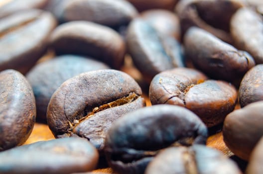 Side view of close up of roasted coffee beans that highlights the texture and surface details of the coffee beans. Coffee beans concept.
