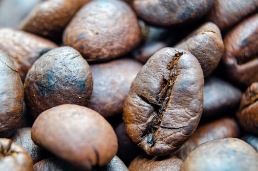 Close up of roasted coffee beans that highlights the texture and surface details of the coffee beans. Morning drinks concept.
