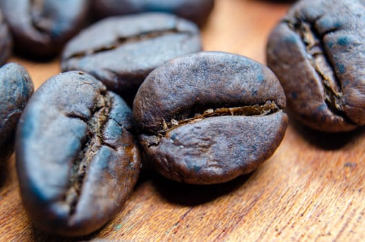 Close up of roasted coffee beans that highlights the texture and surface details of the coffee beans, with a focus on their deep brown color, natural cracks.