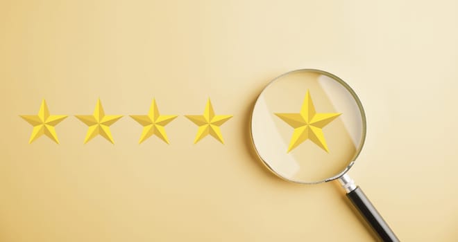Customer uses magnifier glass to focus on five stars icon rating service. Satisfaction evaluation survey and review. Excellent rating. User gives feedback for good business network score.