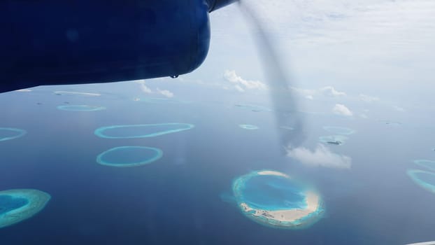 Seaplane is flying over the maldives islands, offering a breathtaking view of the turquoise waters and the coral reefs below, creating a mesmerizing scene of tropical paradise
