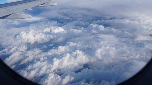 Soaring gracefully above a breathtaking panorama of fluffy cumulus clouds, the airplane wing captures a mesmerizing scene of aerial beauty, showcasing the vastness of the blue sky